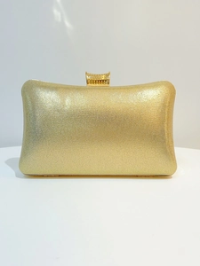 Λεπτομέρεια χρυσού τσαντάκι clutch με γυαλιστερή υφή και κομψό μεταλλικό κούμπωμα