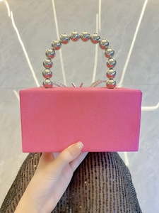 Detailed view of pink silk clutch featuring silver bead handle and bow rhinestone clasp