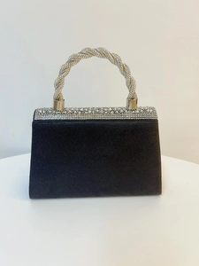 Macro view of black evening clutch bag featuring a sparkling rhinestone knotted handle
