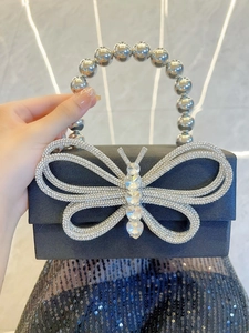 Close-up of luxury black silk evening clutch with large sparkling rhinestone butterfly