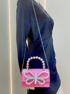 Detail of pink silk evening bag with large rhinestone bow and silver chain strap
