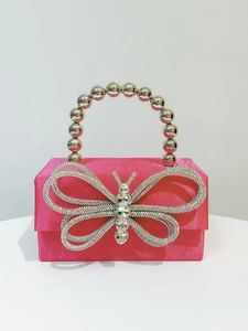 Detail of rose red satin evening clutch with sparkling rhinestone butterfly and beaded handle