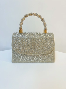 Detail of luxury evening handbag featuring crystal rhinestones and woven gold handle