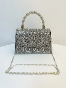Close-up of silver rhinestone evening bag with twisted metal handle and chain strap