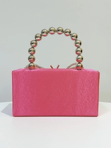 Detail of fuchsia satin evening clutch with metallic silver bead handle and bow clasp