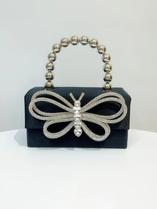Detail of evening clutch bag featuring rhinestone butterfly and metallic beaded handle