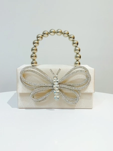 Detail of cream satin evening clutch bag with sparkling rhinestone butterfly and bead handle