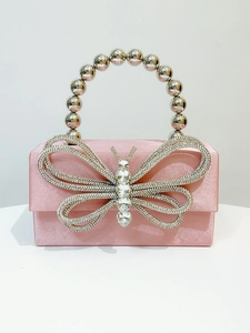 Detail of pink silk evening bag featuring a rhinestone butterfly buckle and bead handle