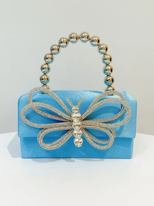Detail of light blue silk evening bag with crystal butterfly and silver beaded handle