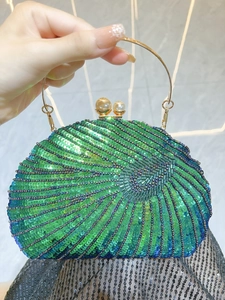 Detail of beaded evening clutch featuring green sequins and elegant pearl clasp closure