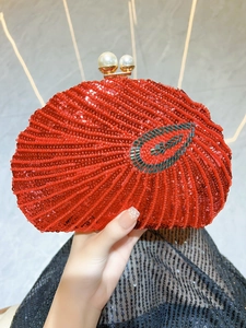 Close-up of red beaded evening bag with leaf patterns and large pearl clasp detail