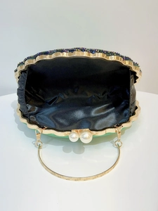 Detail of beaded evening clutch with pearl clasp, golden frame and black satin lining