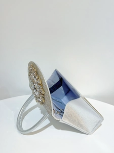 Détail du sac de soirée argenté avec ornement en strass et bandoulière chaîne en métal