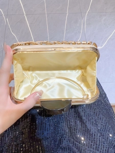 Elegant gold evening clutch bag with intricate metal carving and satin lining
