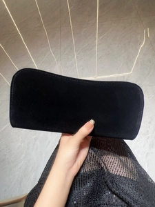 Close-up of black velvet rectangular clutch bag held against a marble background