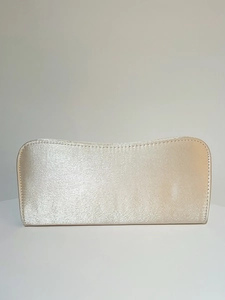 Detail shot of elegant champagne satin evening clutch with smooth pearlescent texture