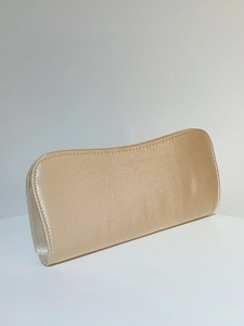 Detail of champagne gold satin evening clutch with elegant curved top and silk texture