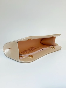 Detail of champagne gold satin clutch bag featuring pink lining and gold chain strap