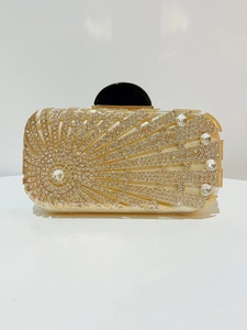 Detailed view of golden evening clutch with sunburst rhinestone patterns and black buckle