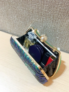 Internal view of a sequined evening bag with pearl clasp showing storage for makeup items
