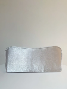 Detail of silver satin evening clutch bag showing wavy top edge and fine stitching