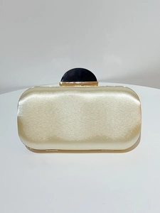 Detail of champagne satin evening clutch with elegant gold frame and dark resin clasp