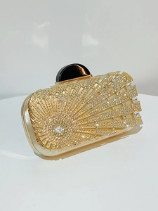 Detail of golden evening clutch with sunburst rhinestone patterns and large black clasp