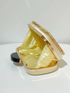 Detail view of the open evening clutch bag with golden metal frame and chain strap