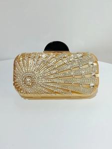 Close-up of golden evening clutch bag with sparkling rhinestone sunburst pattern