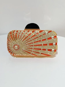 Close-up of red rhinestone evening clutch bag with gold frame and sunburst crystal pattern