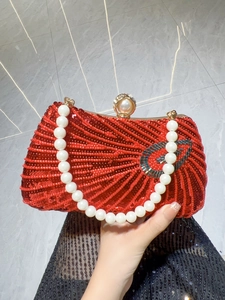 Detailed view of red sequin evening bag with large pearl handle and golden ball clasp
