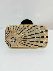 Macro detail of sunburst rhinestone pattern on black metal evening clutch bag