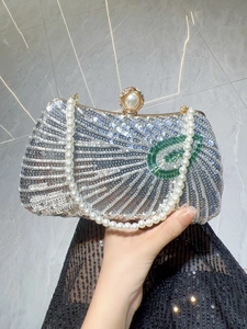 Detail of silver sequin evening bag with pearl clasp and green peacock feather embroidery