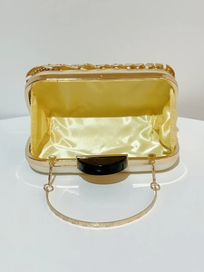 Detail view of cream evening clutch with yellow satin lining and gold leaf relief accents