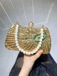 Detail of luxury gold sequin evening bag with large pearl handle and ball clasp closure