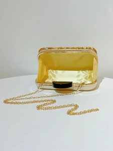 Detail of gold evening clutch with hollowed-out floral pattern and yellow satin lining