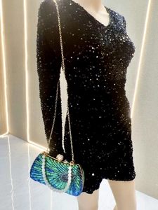 Detail of teal beaded fan-shaped evening clutch with pearl handle and sequin dress