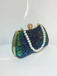 Detailed close-up of peacock feather beadwork on luxury evening clutch with pearl handle