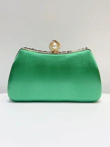 Detail of emerald green satin evening clutch with pearl clasp and black gem accents