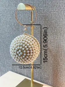 Spherical white pearl clutch bag with golden ring handle and elegant metal frame