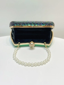 Detailed view of green sequined evening clutch bag with pearl handle and metal clasp