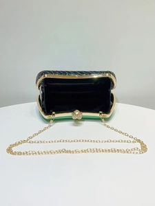 Detail view of emerald sequined evening bag with golden chain and open interior