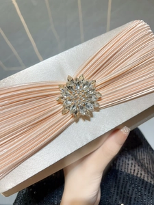 Détail de la pochette de soirée en satin champagne avec boucle soleil en strass