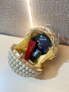Detail showing pearl beaded clutch interior with yellow satin lining and gold frame