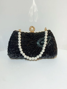 Detail of black sequined evening bag with large pearl clasp and golden metal hardware
