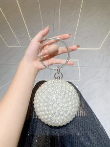 Detail of round pearl evening bag featuring a sparkling rhinestone circular ring handle