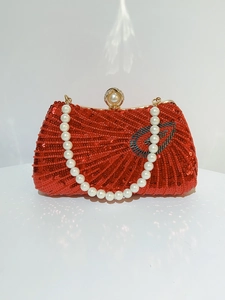 Detail of red sequin evening clutch bag with heart motif and luxury pearl handle