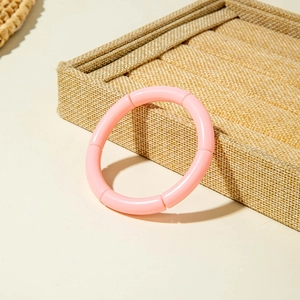 Close-up of pink bamboo-style stretch bangle resting on a textured jewelry display box