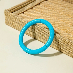 Close-up of a bright blue segmented acrylic bangle on a linen texture display tray