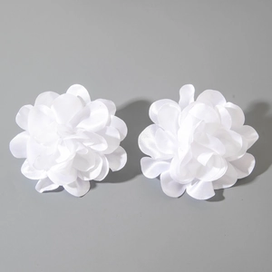 Gros plan détaillé de boucles d'oreilles camélia en satin blanc aux pétales superposés